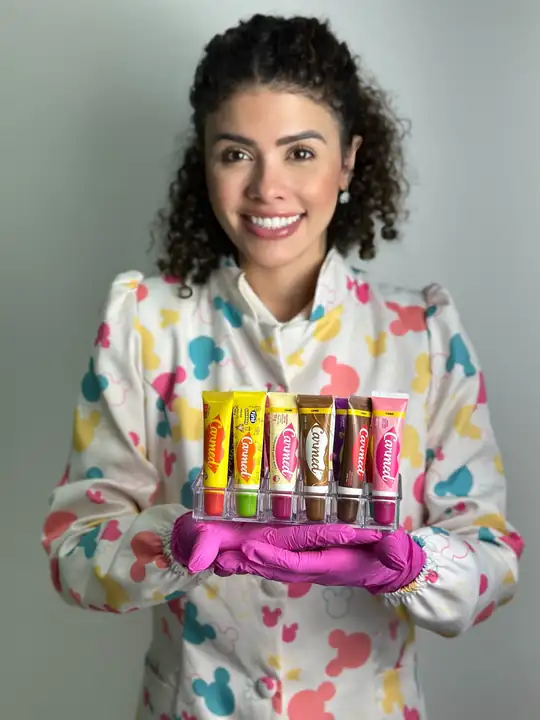 Dra. Gabriela Santos Barreto, dentista infantil na zona leste de SP, com jaleco colorido e luvas rosa